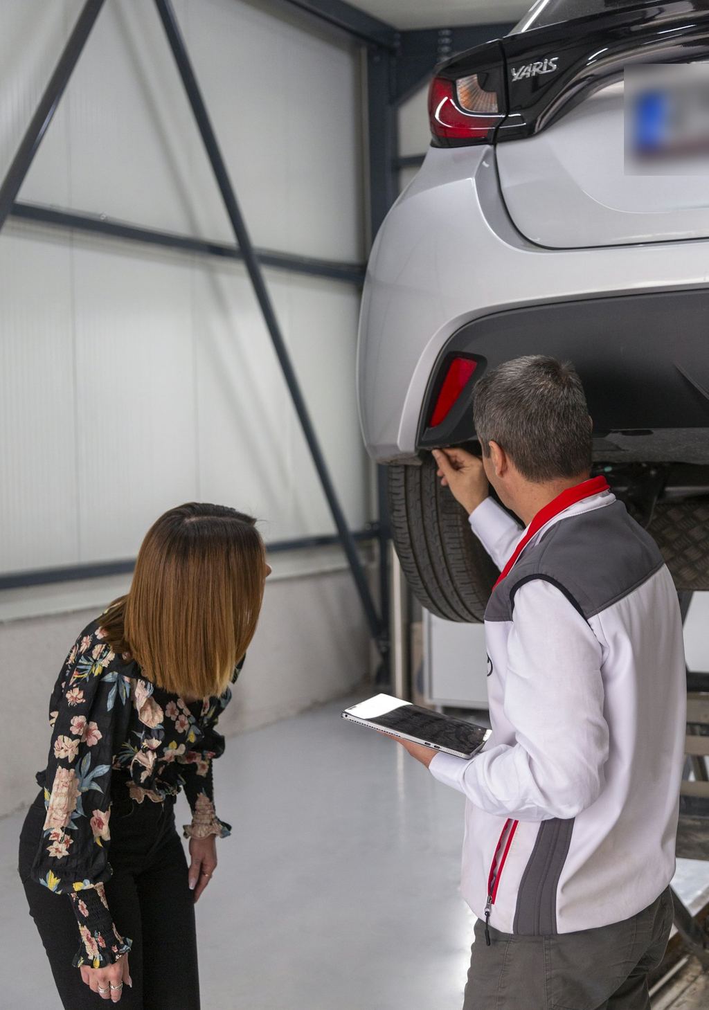 A service advisor with a tablet showing a customer her car