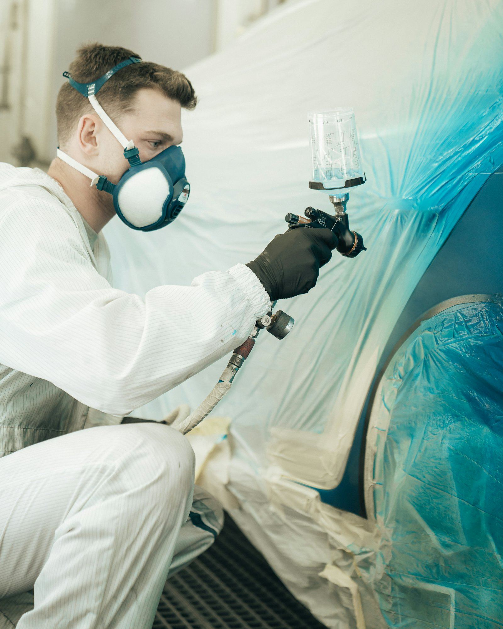 A painter spraying a panel in a paint booth