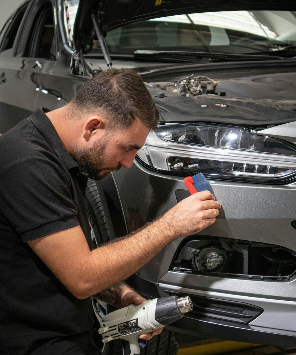 A technician checking a car’s headlight