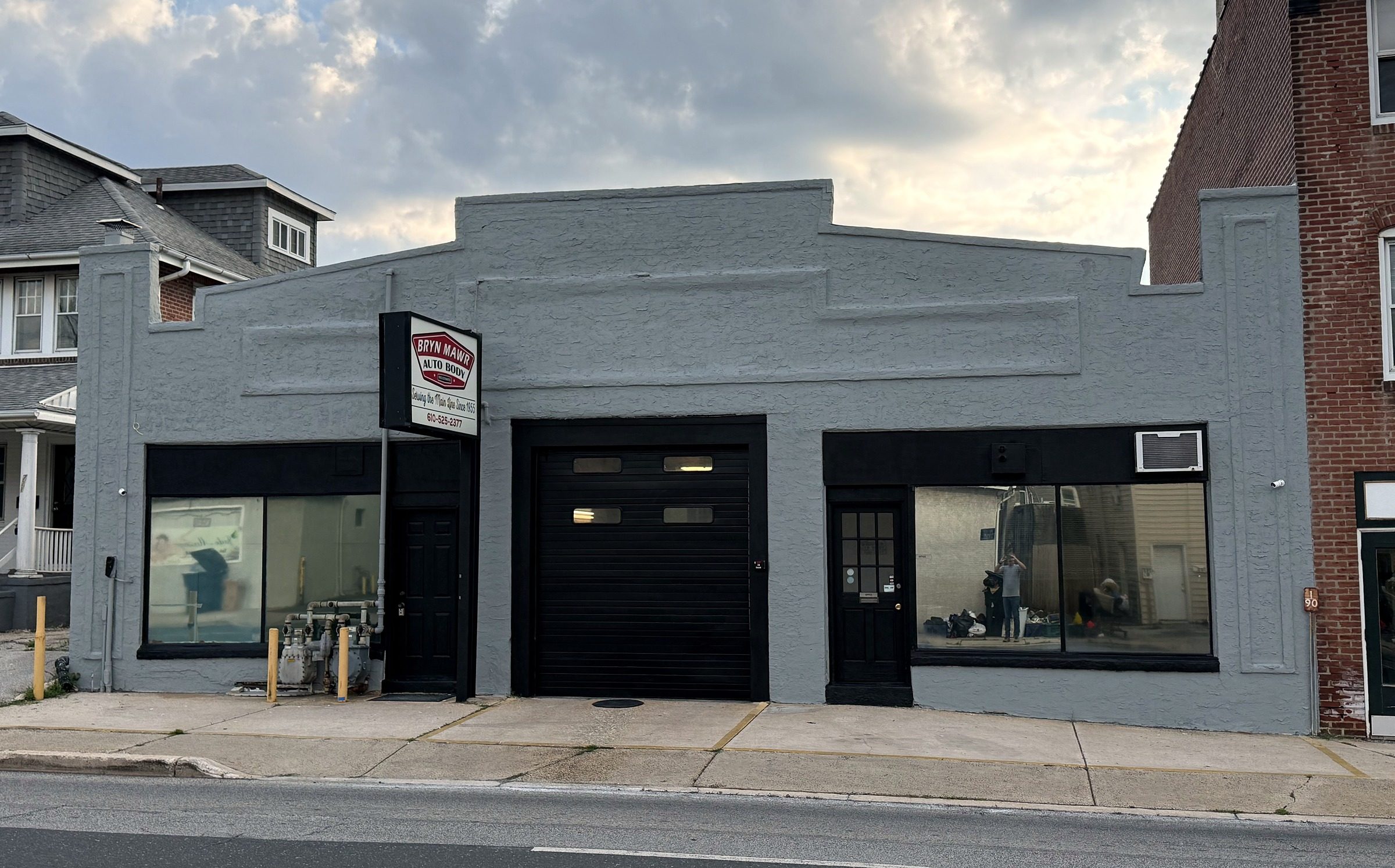 The Bryn Mawr Auto Body building on West Haverford Road: a grey storefront with a black bay door and the red shop sign