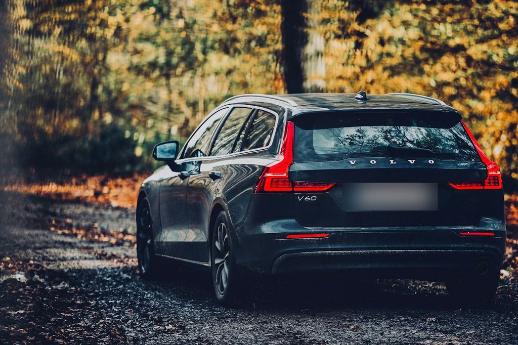 A dark Volvo wagon on a leafy road